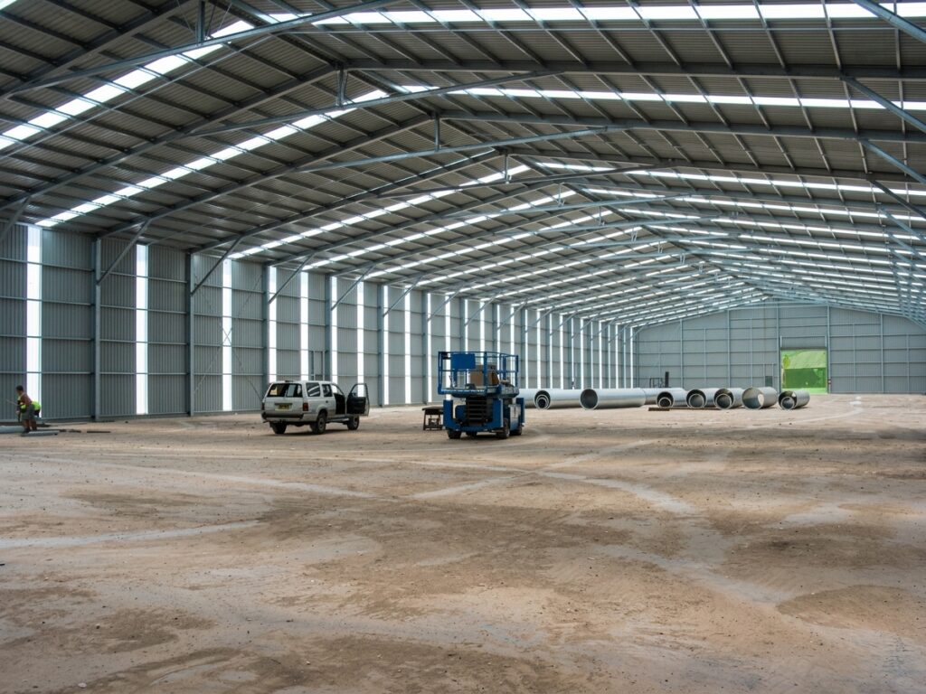 PEB Structures in Pakistan, PEB Building Cost in Pakistan, Wide interior view of a large-span pre-engineered steel warehouse shed featuring translucent roof panels and clean industrial flooring by M. Siddique Sons Engineering.