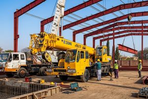 Heavy-duty yellow construction cranes assembling pre-engineered steel structures for M. Siddique Sons.